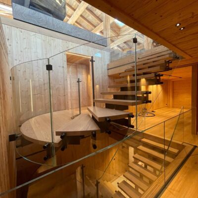 Escalier suspendu à limon central cintré & garde-corps en verre - Chalet privé - Megève France